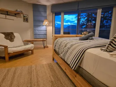 a bedroom with a bed and a chair and a window at Madeira Park Oceanview Suites in Madeira Park
