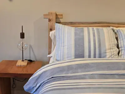 a bed with a wooden headboard and a lamp on a table at Madeira Park Oceanview Suites in Madeira Park