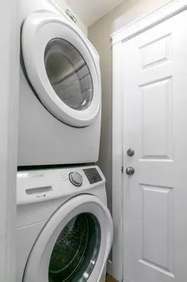 a washing machine in a white room with a door at Great 1-bedroom Suite Near Downtown Langford in Victoria