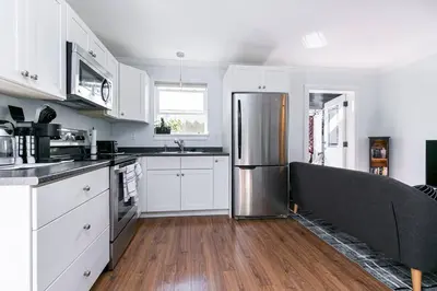 a kitchen with white cabinets and a stainless steel refrigerator at Great 1-bedroom Suite Near Downtown Langford in Victoria