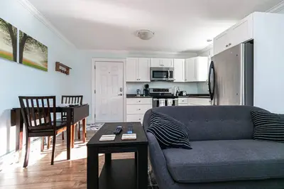 a living room with a couch and a table and a kitchen at Great 1-bedroom Suite Near Downtown Langford in Victoria