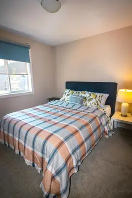 a bedroom with a bed with a striped blanket and a window at Entire Home AC 4Beds Sleeps 8 Double Garage Near WEM Free Wifi & Netflix in Edmonton