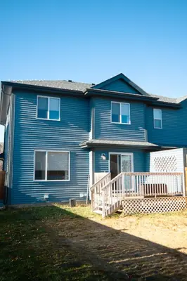 a blue house with a white porch and a yard at Entire Home AC 4Beds Sleeps 8 Double Garage Near WEM Free Wifi & Netflix in Edmonton