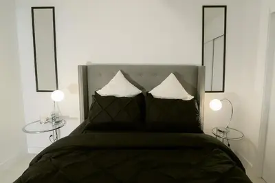 a bedroom with a bed with two tables and two mirrors at Vibrant & Modern Loft-style Walkout Near LRT in Calgary