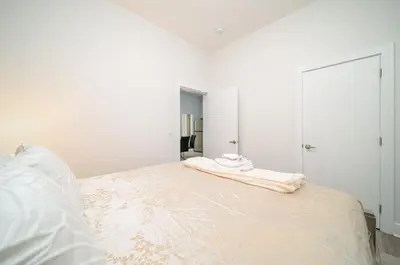 a white bedroom with a bed with two towels on it at William Place in Surrey
