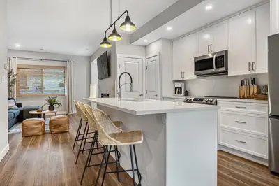 a kitchen with white cabinets and a kitchen island with bar stools at Serene Peaks, Private Hot Tub, Peaceful in Radium Hot Springs