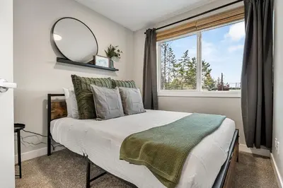 a bedroom with a bed with a mirror and a window at Serene Peaks, Private Hot Tub, Peaceful in Radium Hot Springs