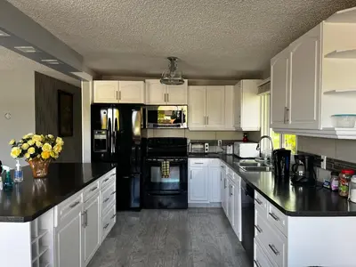 a kitchen with white cabinets and black appliances at hunter' s new home! in Calgary