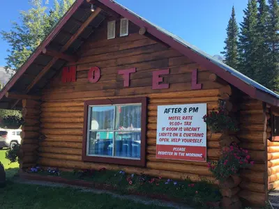 a log building with a sign on it at Double G Service in Muncho Lake