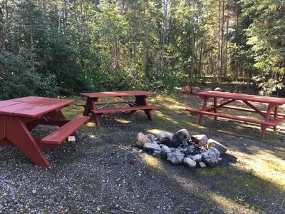 two picnic tables and a fire pit in a park at Double G Service in Muncho Lake