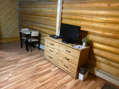 a room with a tv on a dresser with a table at Double G Service in Muncho Lake