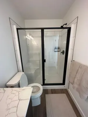 a bathroom with a toilet and a glass shower at The Evergreen House in Red Deer