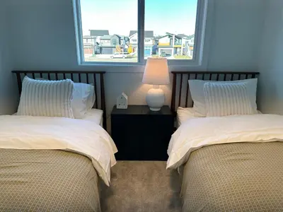 two beds in a room with two windows at The Evergreen House in Red Deer