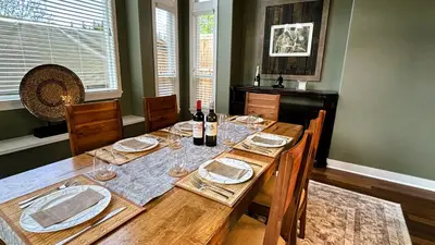 a dining room with a wooden table with wine bottles at Metropolitan Dream Stay with Saltwater Pool and Hot Tub in Surrey