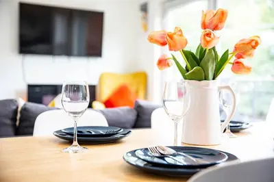 a table with two glasses and a vase with flowers at Reved Up & Out - Remarkable Two Bedroom Condo in Revelstoke