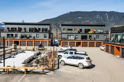 a parking lot with cars parked in front of a building at Reved Up & Out - Remarkable Two Bedroom Condo in Revelstoke