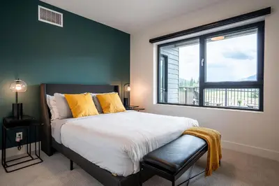 a bedroom with a bed and a large window at Revy's Peak Condo - Hot Tub with View in Revelstoke