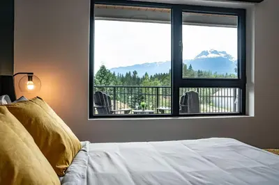 a bedroom with a bed and a large window at Revy's Peak Condo - Hot Tub with View in Revelstoke