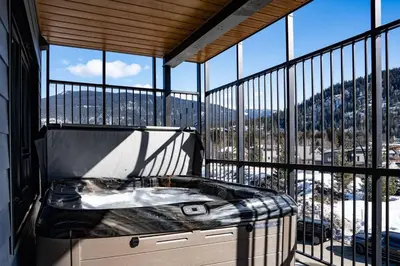 a balcony with a hot tub in front of a large window at Rocky Ridge Getaway - Modern Getaway in Revelstoke in Revelstoke