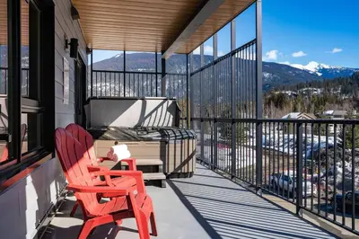 two red chairs sitting on the balcony of a house at Rocky Ridge Getaway - Modern Getaway in Revelstoke in Revelstoke