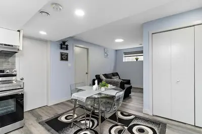 a kitchen and living room with a table and a couch at The Cozy Cove - Modern Private Basement Suite with Comfort & Charm, Free Parking, WiFi, Netflix Close to airport & 18 minutes to West Edmonton Mall in Edmonton