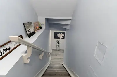 a staircase in a home with white walls and wooden floors at The Cozy Cove - Modern Private Basement Suite with Comfort & Charm, Free Parking, WiFi, Netflix Close to airport & 18 minutes to West Edmonton Mall in Edmonton