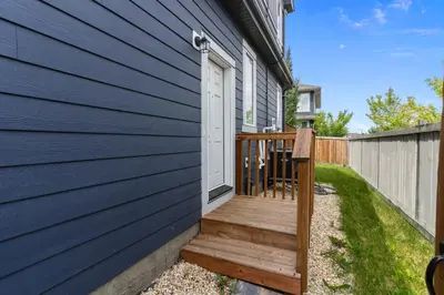 a wooden porch with a white door on the side of a house at The Cozy Cove - Modern Private Basement Suite with Comfort & Charm, Free Parking, WiFi, Netflix Close to airport & 18 minutes to West Edmonton Mall in Edmonton