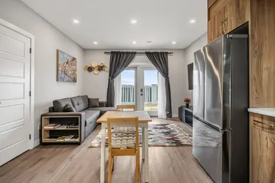 a kitchen and living room with a stainless steel refrigerator at Sunny Walk-out Unit, Free HiSpeed Wi-Fi and Parking, Near Grocery in Calgary