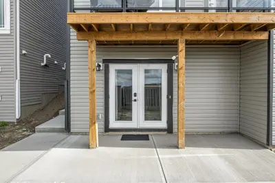 a garage with a white door and a wooden pergola at Sunny Walk-out Unit, Free HiSpeed Wi-Fi and Parking, Near Grocery in Calgary