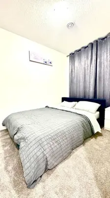 a bedroom with a large bed with a blue curtain at The Cozy Nest in Calgary