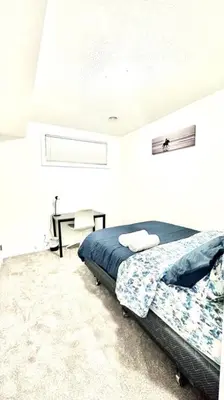 a bedroom with a bed in a white room at The Cozy Nest in Calgary