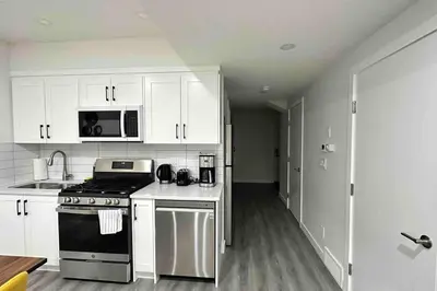 a kitchen with white cabinets and a stove and microwave at The Cozy Nest in Calgary