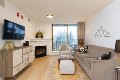 a living room with a couch and a tv and a fireplace at Renovated 1Bed-1Bath in Village with Pool, Hot Tub, and Sauna in Whistler