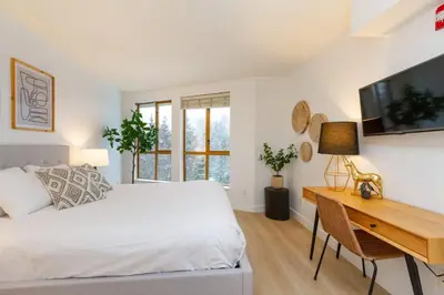 a bedroom with a bed and a desk and a television at Renovated 1Bed-1Bath in Village with Pool, Hot Tub, and Sauna in Whistler