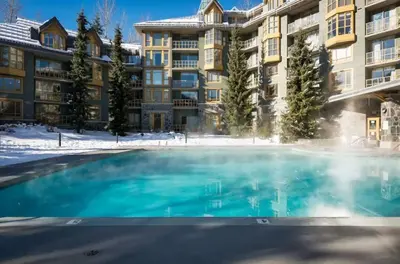a swimming pool in front of an apartment building at Renovated 1Bed-1Bath in Village with Pool, Hot Tub, and Sauna in Whistler