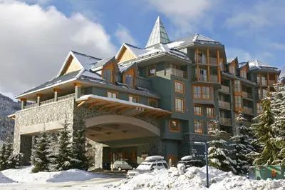 a large building in the snow with a car parked in front at Renovated 2Bed-2Bath in Village with Pool, Hot Tub, and Sauna in Whistler