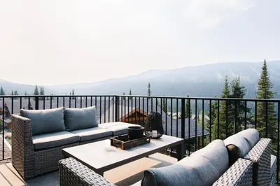 a patio with couches and a table on a balcony at New! Luxury, Top Floor, Ski in/Ski Out, Private Hot Tub and Mountain Views in Sun Peaks