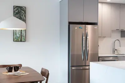a kitchen with a stainless steel refrigerator and a table at Wildflower Retreat by Revelstoke Vacations in Revelstoke