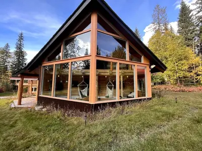 a house with large glass windows in a field at Golden Cabin - Hot Tub - Games Barn - Theatre in Golden