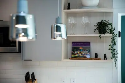 a kitchen with white cabinets and a shelf with wine glasses at Ski & Tee Retreat Bright Three Bedroom and Hot Tub in Revelstoke