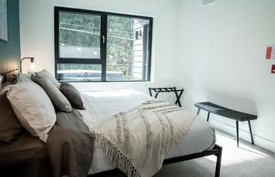 a white bedroom with a bed and a window at Ski & Tee Retreat Bright Three Bedroom and Hot Tub in Revelstoke
