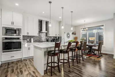 a kitchen with white cabinets and a table and chairs at Luxury Retreat For Large Groups in Calgary