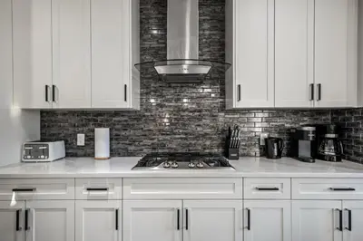 a kitchen with white cabinets and a stove top oven at Luxury Retreat For Large Groups in Calgary