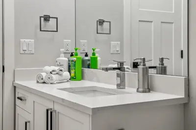 a white bathroom with a sink and a mirror at Luxury Retreat For Large Groups in Calgary