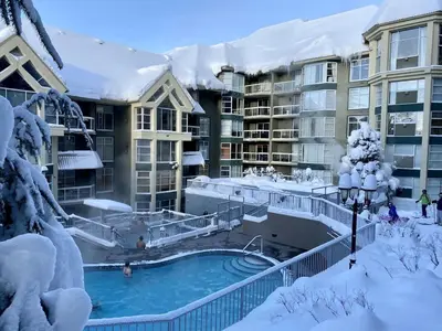 a resort with a swimming pool in the snow at Woodrun Lodge 216 | Renovated Ski-In Ski-Out Condo w/ Free Parking, Pool, Hot Tub, & Gym in Whistler