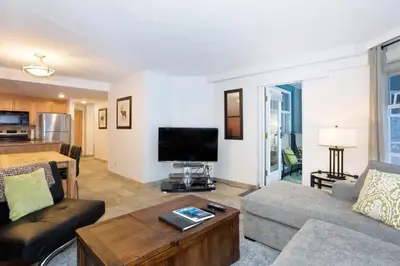 a living room with a couch and a tv at Woodrun Lodge 216 | Renovated Ski-In Ski-Out Condo w/ Free Parking, Pool, Hot Tub, & Gym in Whistler