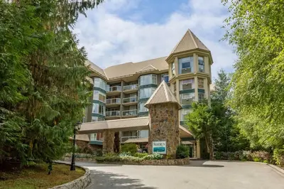a large apartment building with a tower at Woodrun Lodge 217 | Ski-In Ski-Out Condo - Walk to Upper Village w/ Hot Tub, Pool + Free Parking in Whistler