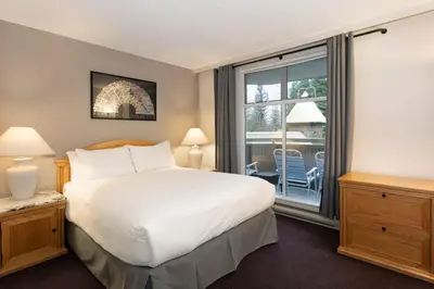 a bedroom with a bed and a large window at Woodrun Lodge 217 | Ski-In Ski-Out Condo - Walk to Upper Village w/ Hot Tub, Pool + Free Parking in Whistler