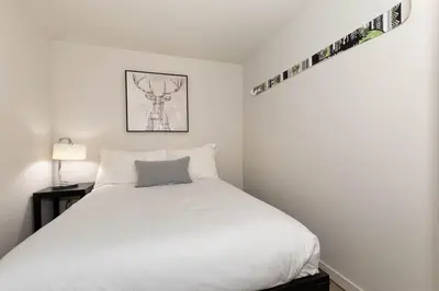 a bedroom with a white bed with a gray pillow at Woodrun Lodge 412 | Ski-In-Ski-Out, Pool, Hot Tub, & Free Parking in Whistler