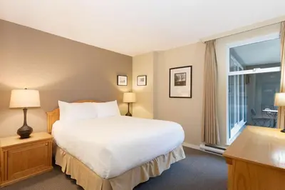 a bedroom with a large bed and a window at Woodrun Lodge 211 | Ski-In Ski-Out Condo w/ Heated Pool, Hot Tub, Parking, & Gym in Whistler